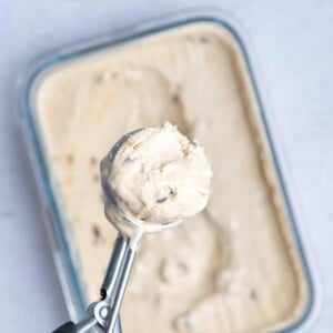 Scooping cottage cheese ice cream from a tub.