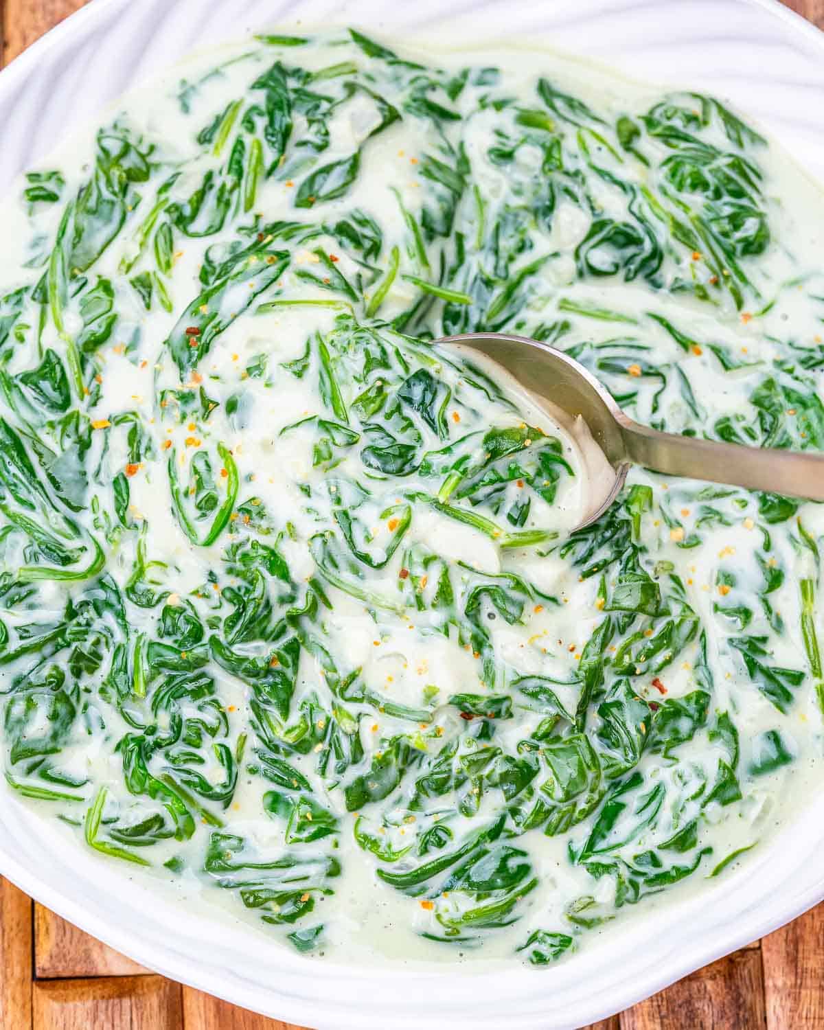 creamed spinach in a dish with spoon in the dish.
