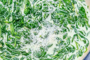 adding parmesan cheese over the creamy spinach.