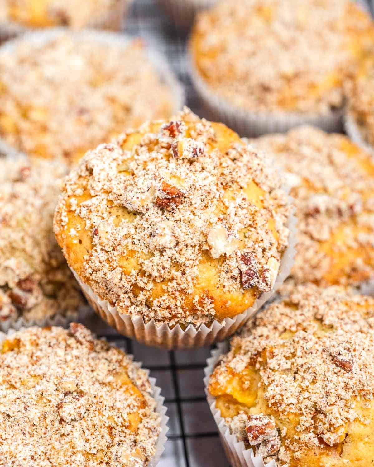 peach muffins stacked over each other on a cooling rack.