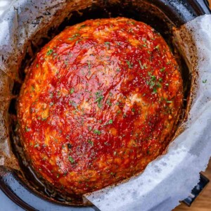 A slow cooker filled with an oval-shaped turkey meatloaf topped with ketchup glaze.