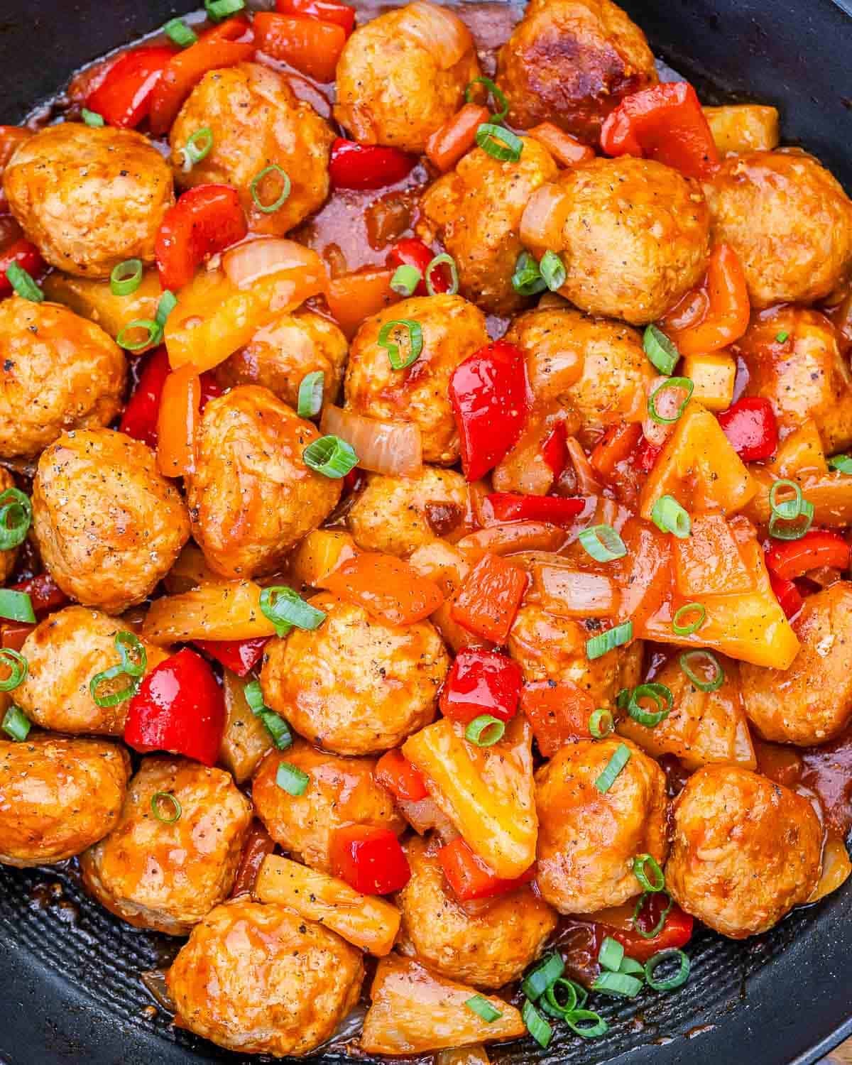 Sweet and sour chicken meatballs with pineapple and bell peppers in a skillet