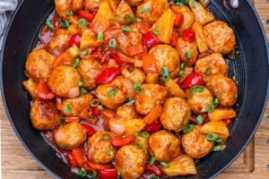 a wok pan filled with sweet and sour meatballs.