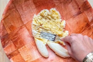Mashing 2 bananas in a bowl.