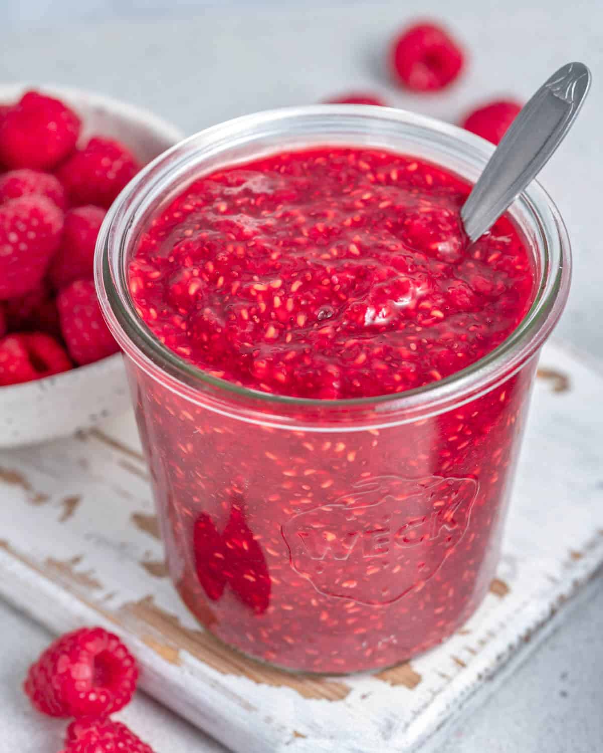 A jar of raspberry jam with a spoon in it.