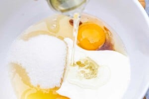 pouring oil into a bowl with buttermilk and eggs.