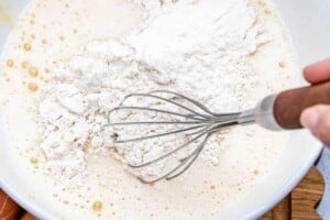 mixing in the flour with the egg and milk batter.