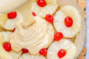 pouring batter into the pan with the pineapple.