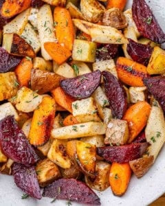 A close up of roasted beets, carrots, parsnips, celery root, and potatoes garnished with thyme.