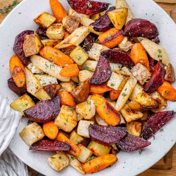Roasted chopped root veggies served in a white round bowl.