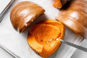 scooping pumpkin from flesh of cooked pumpkin.
