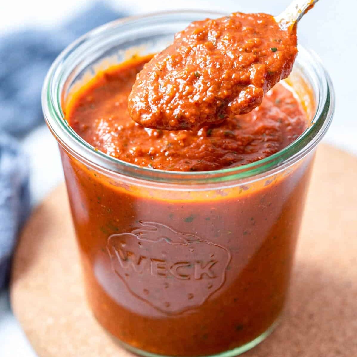 Ranchero sauce in a jar with a spoon dipped in the jar.