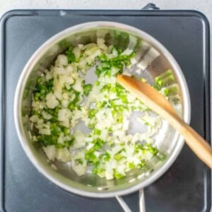 sauteing onion and green peppers in a pan.