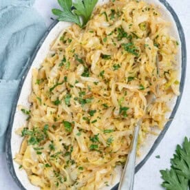 sauteed cabbage served on a plate topped with chopped parsley.