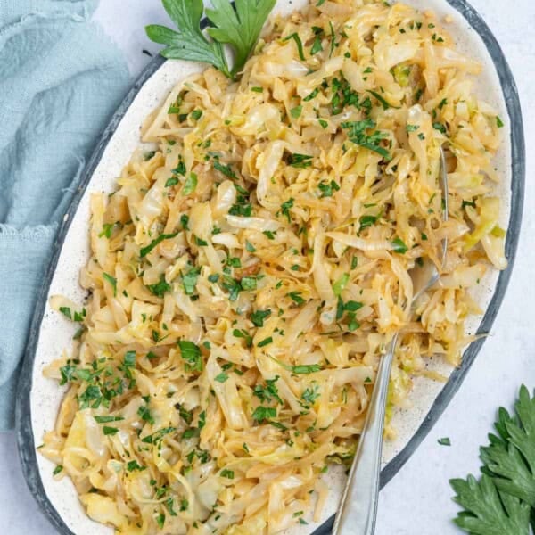 sauteed cabbage served on a plate topped with chopped parsley.